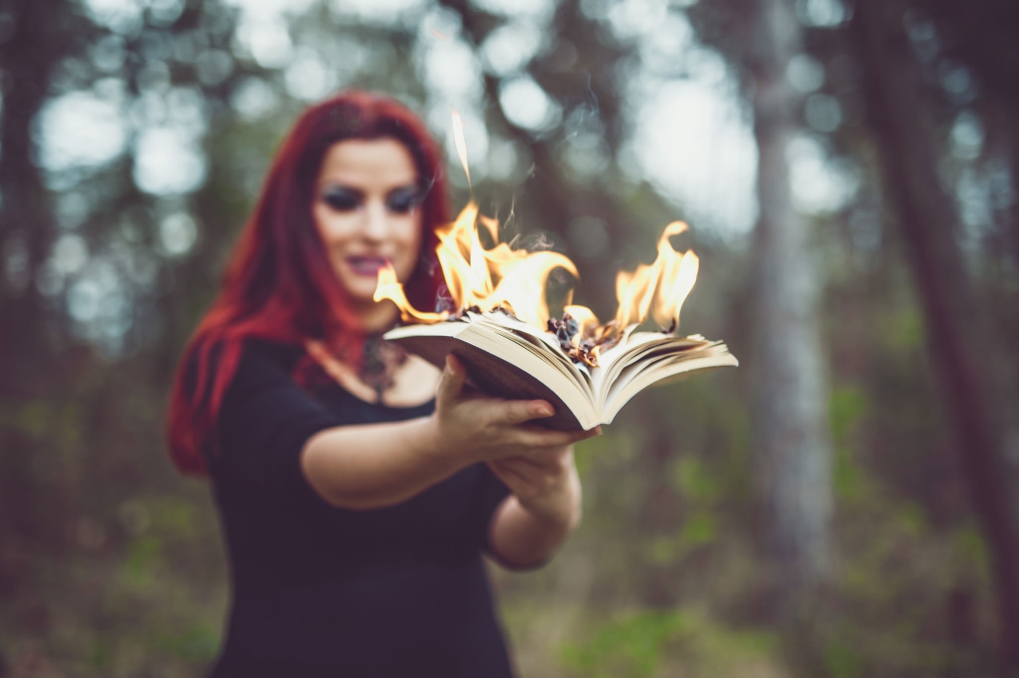Grimoire, herbs, and candles arranged on a dark surface for witchcraft practice